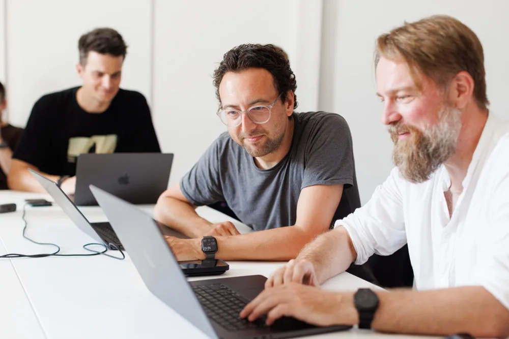 Drei Teammitglieder arbeiten gemeinsam vor einem Laptop